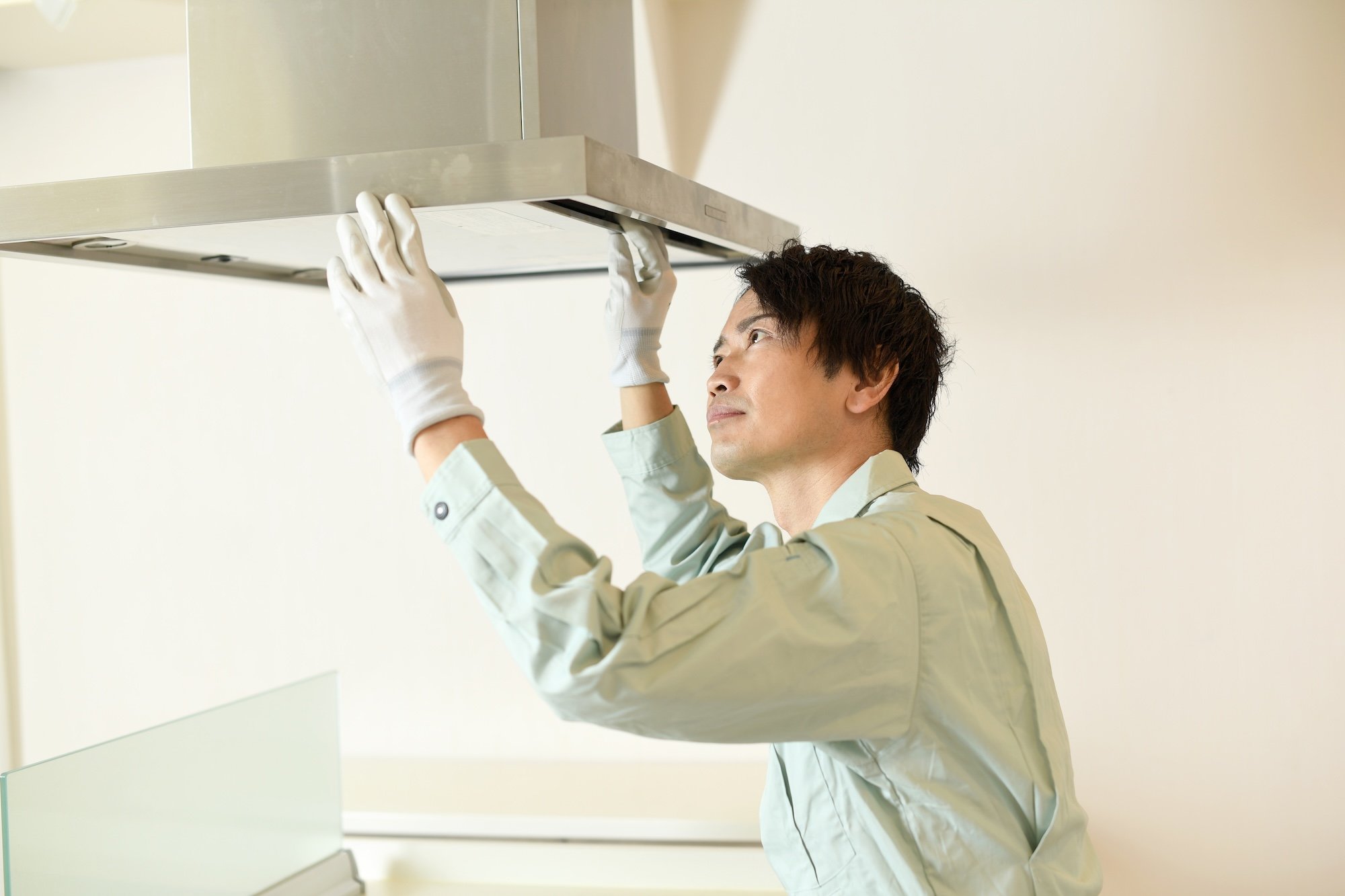 キッチンのレンジフードを設置する作業員